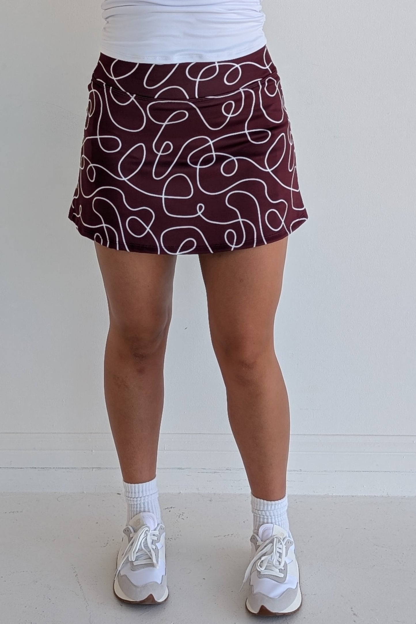 Form Fitting maroon miniskirt with scribbles print and built in shorts and pockets; great for gameday or hanging out with friends.