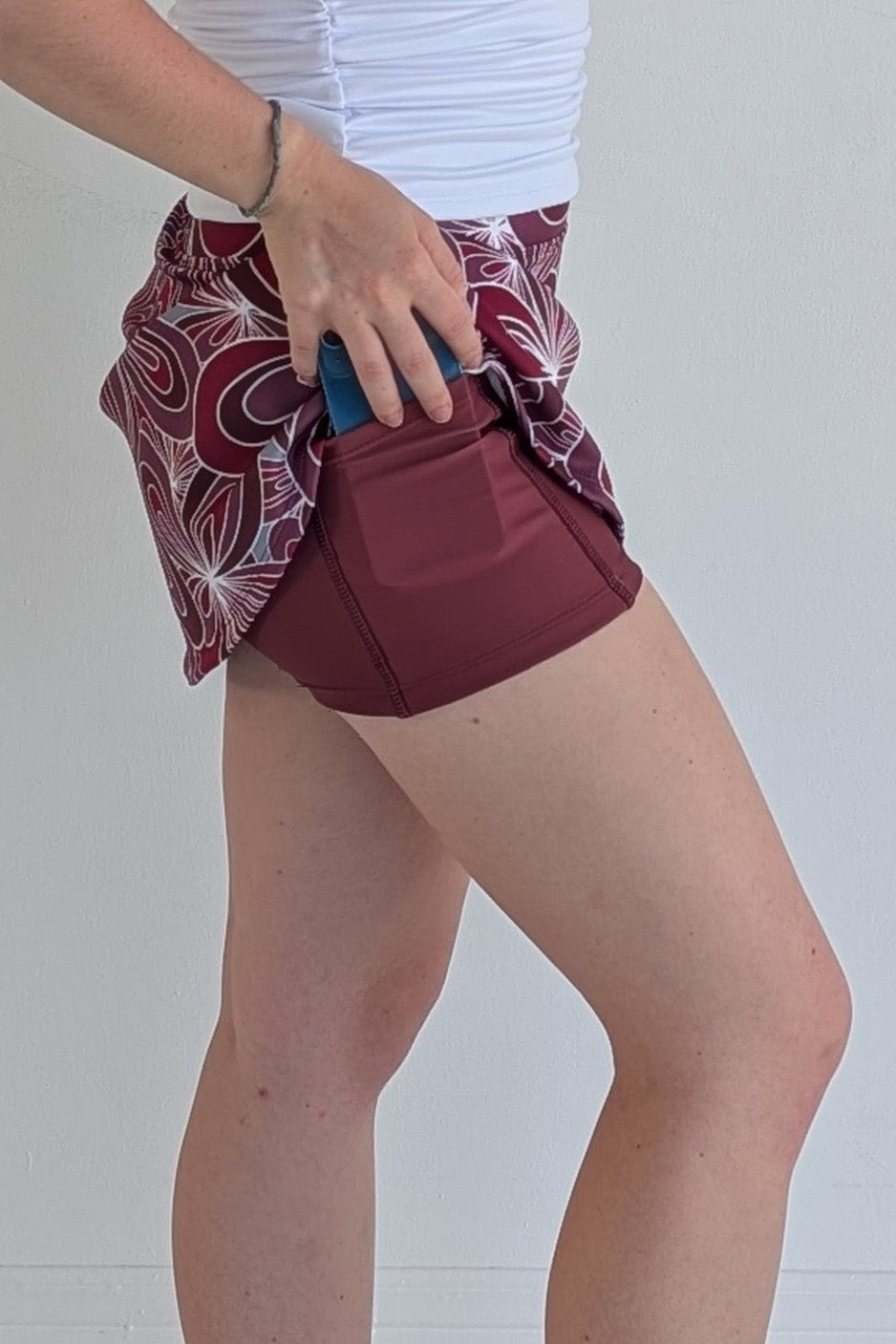 Form Fitting maroon miniskirt with 70's inspired flower print and built in shorts and pockets; great for gameday or hanging out with friends.