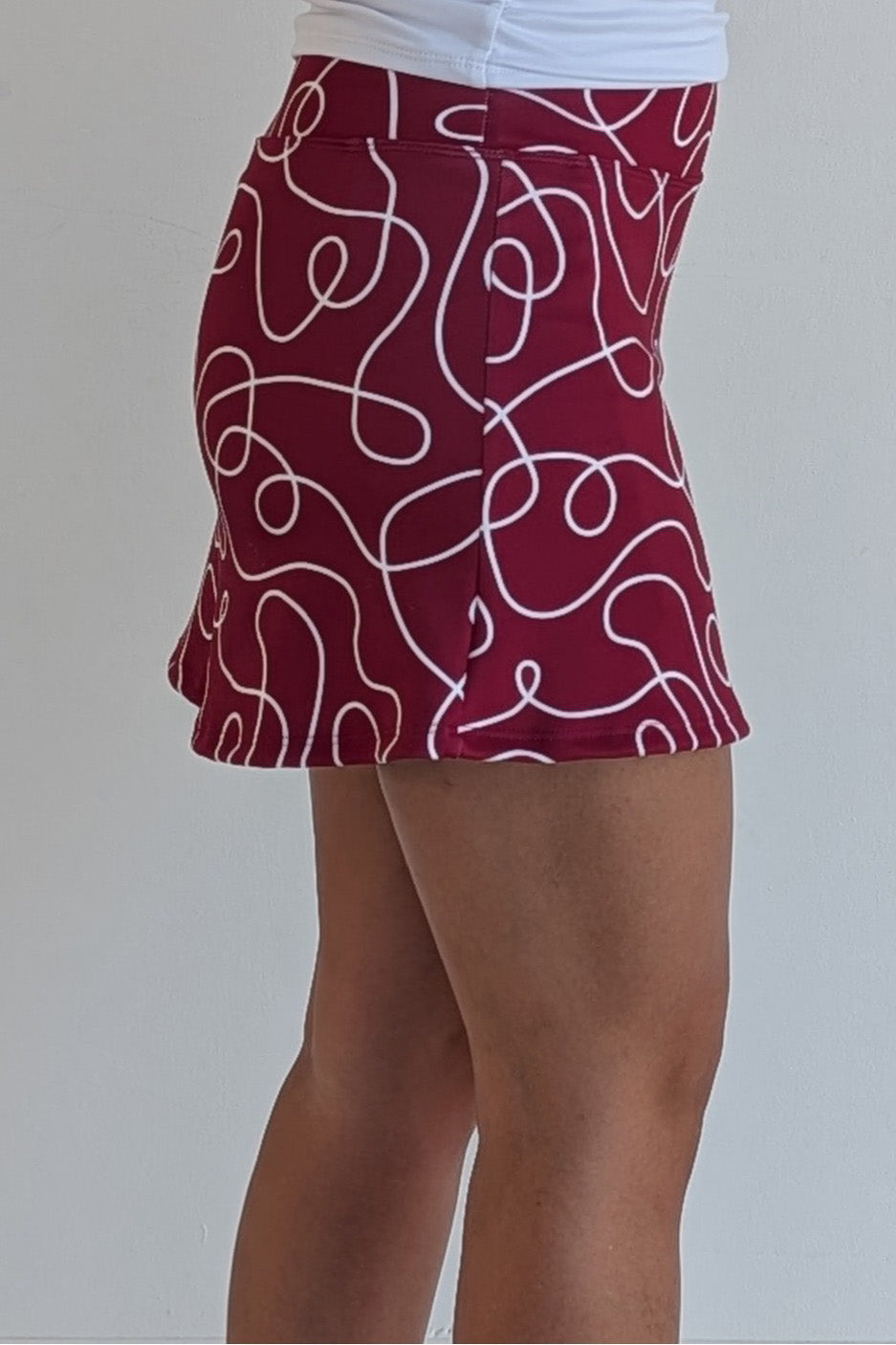 Form Fitting crimson miniskirt with scribbles print and built in shorts and pockets; great for gameday or hanging out with friends.