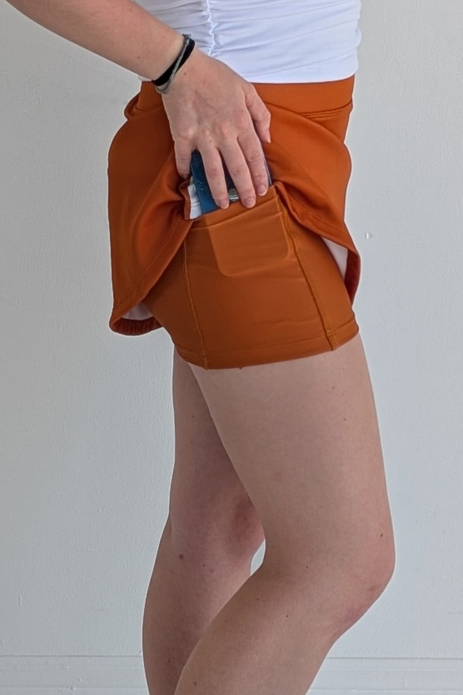 Form Fitting burnt orange miniskirt with side stripes and built in shorts and pockets; great for gameday or hanging out with friends.