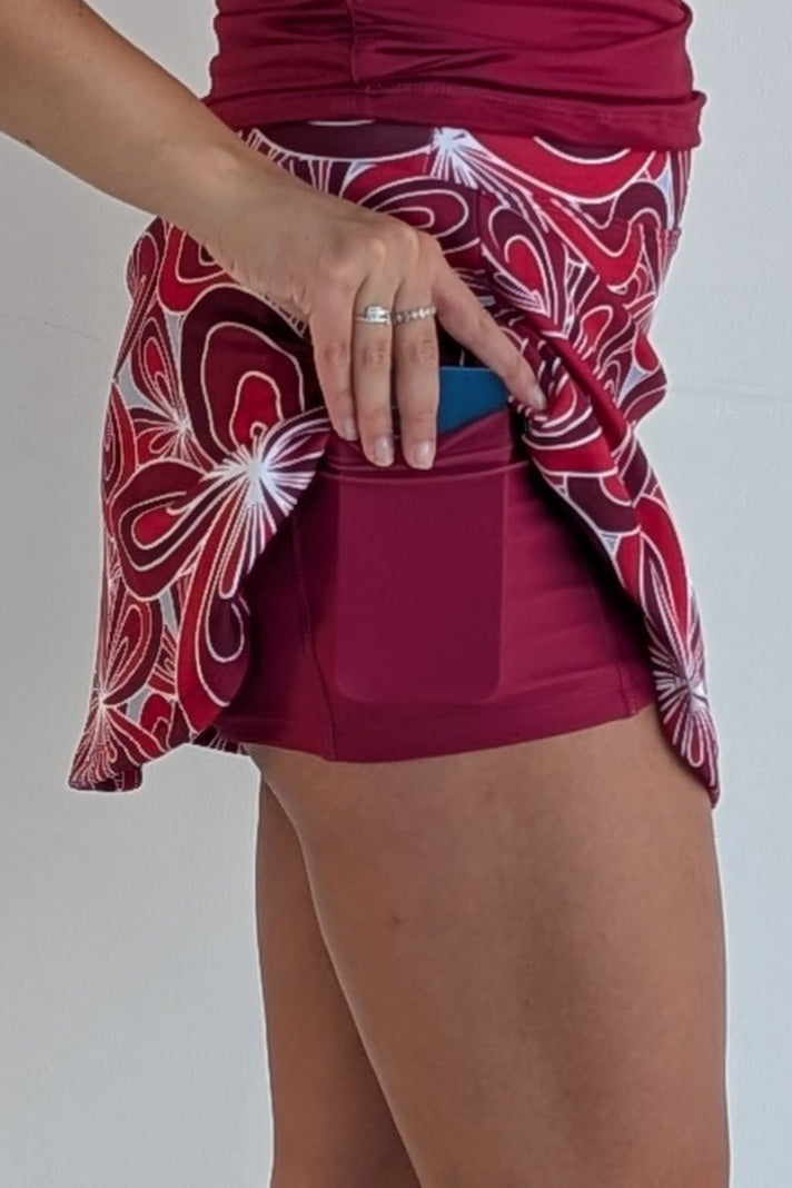 Relaxed back crimson miniskirt with 70's inspired flower print and built in shorts and pockets; great for gameday or hanging out with friends.