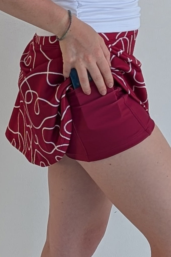 Relaxed back crimson miniskirt with scribbles print and built in shorts and pockets; great for gameday or hanging out with friends.