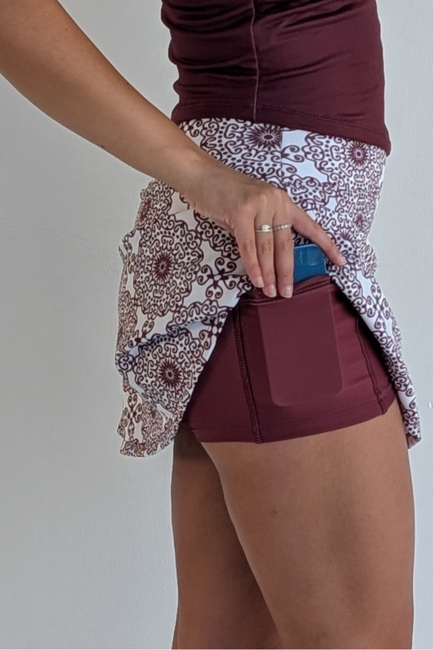 Relaxed back maroon miniskirt with scroll print and built in shorts and pockets; great for gameday or hanging out with friends.