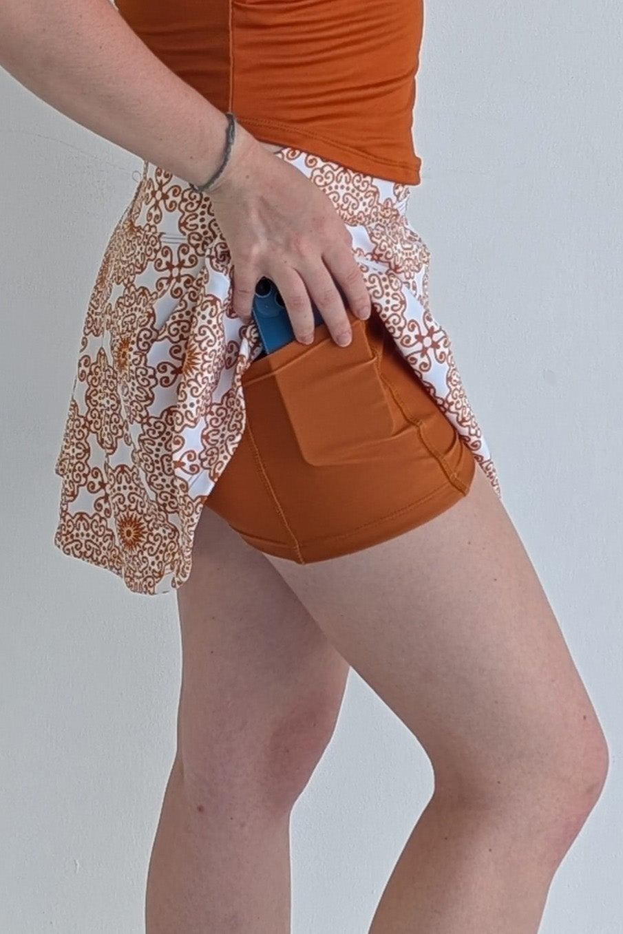 Full bodied burnt orange miniskirt with scroll print and built in shorts and pockets; great for gameday or hanging out with friends.