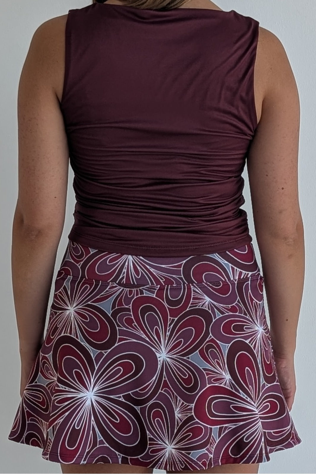 Maroon top and floral patterned skirt on a plain background