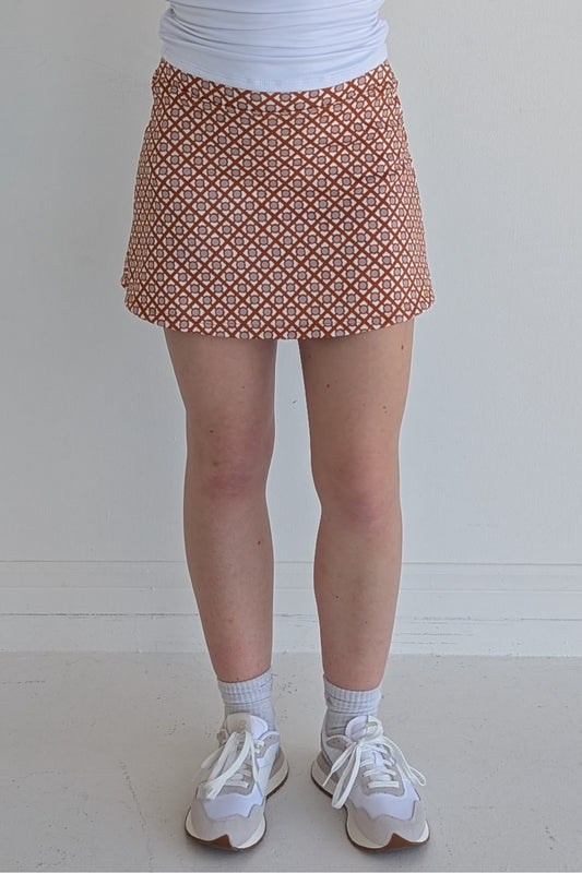 Form Fitting burnt orange miniskirt with geometric print and built in shorts and pockets; great for gameday or hanging out with friends.