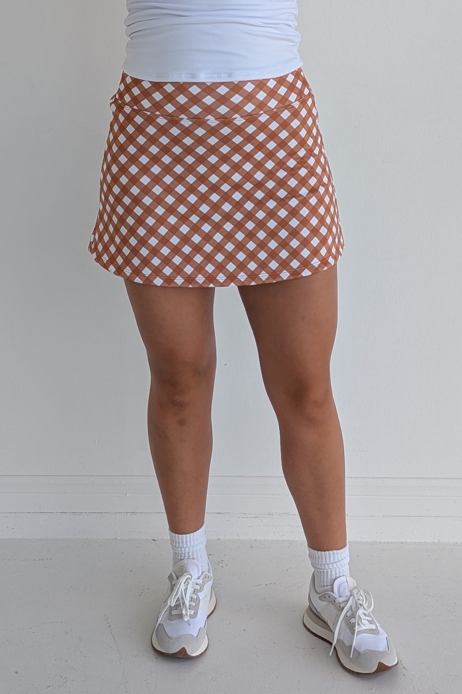 Form Fitting burnt orange gingham miniskirt with  built in shorts and pockets; great for gameday or hanging out with friends.