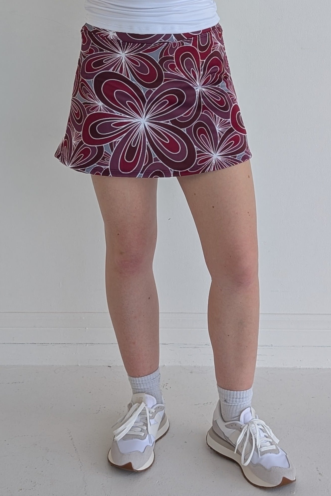 Form Fitting maroon miniskirt with 70's inspired flower print and built in shorts and pockets; great for gameday or hanging out with friends.