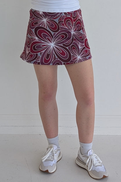 Form Fitting maroon miniskirt with 70's inspired flower print and built in shorts and pockets; great for gameday or hanging out with friends.