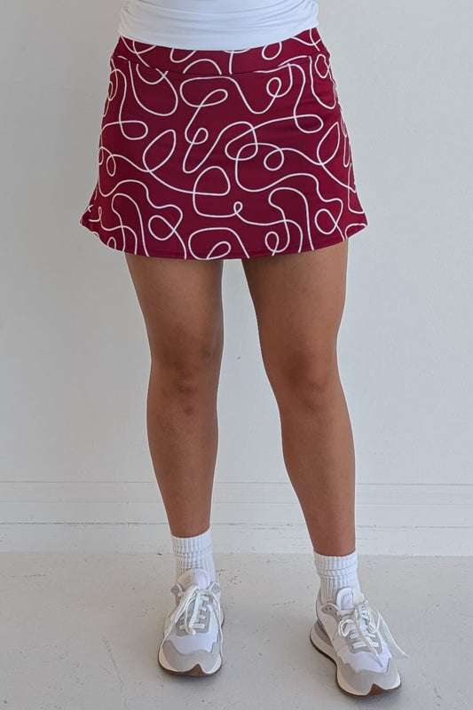 Form Fitting crimson miniskirt with scribbles print and built in shorts and pockets; great for gameday or hanging out with friends.