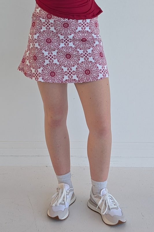 Form Fitting crimson miniskirt with scroll print and built in shorts and pockets; great for gameday or hanging out with friends.