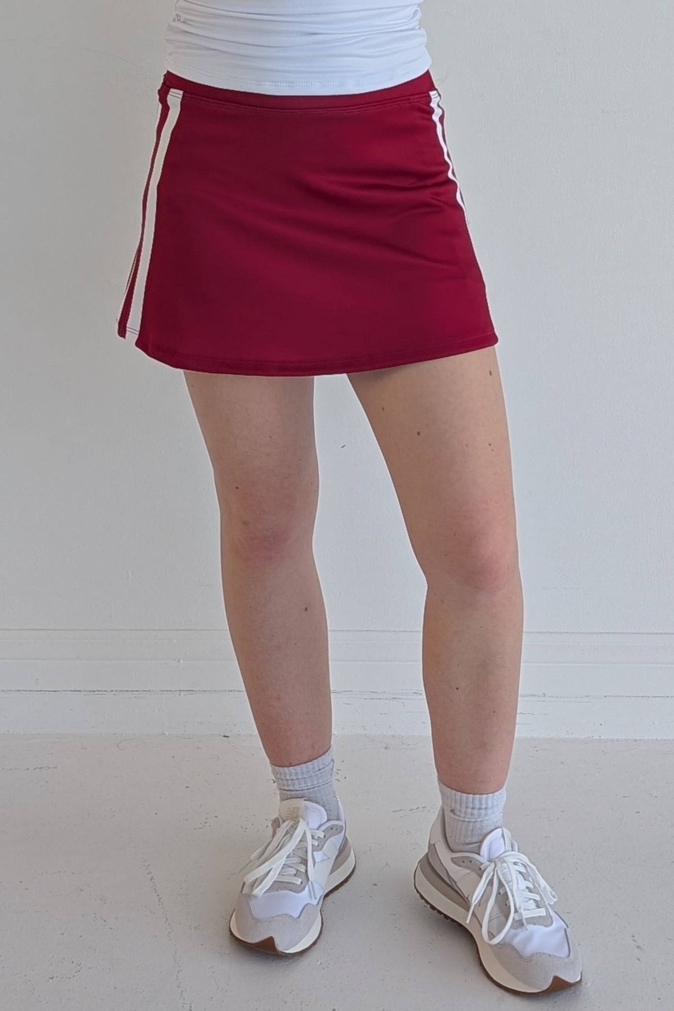 Form Fitting crimson miniskirt with side stripes and built in shorts and pockets; great for gameday or hanging out with friends.