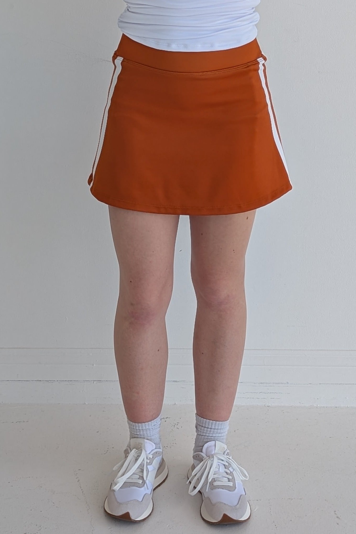 Form Fitting burnt orange miniskirt with side stripes and built in shorts and pockets; great for gameday or hanging out with friends.