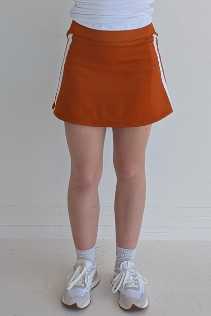 Form Fitting burnt orange miniskirt with side stripes and built in shorts and pockets; great for gameday or hanging out with friends.