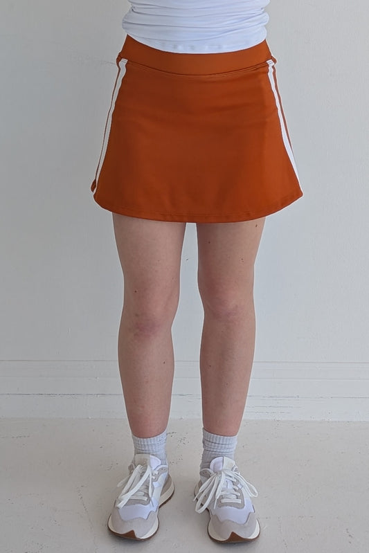 Form Fitting burnt orange miniskirt with side stripes and built in shorts and pockets; great for gameday or hanging out with friends.
