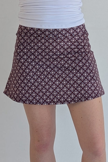 Form Fitting maroon miniskirt with geometric print and built in shorts and pockets; great for gameday or hanging out with friends.