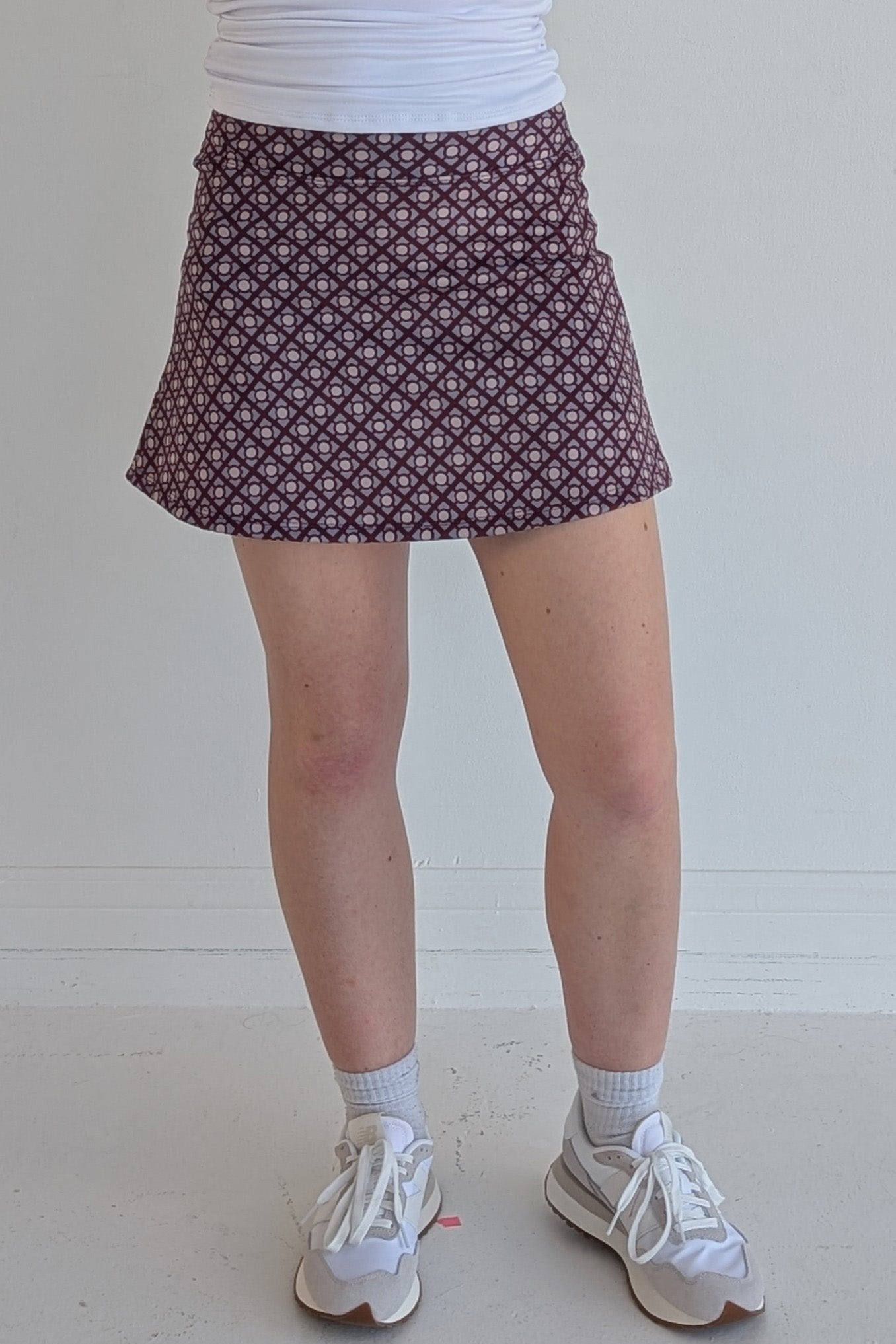 Form Fitting maroon miniskirt with geometric print and built in shorts and pockets; great for gameday or hanging out with friends.