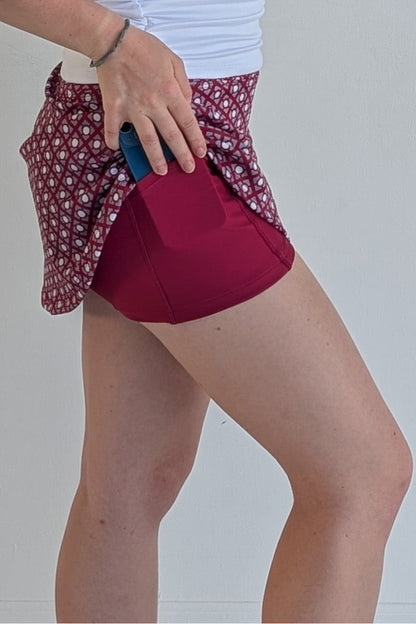 Form Fitting crimson miniskirt with geometric print and built in shorts and pockets; great for gameday or hanging out with friends.