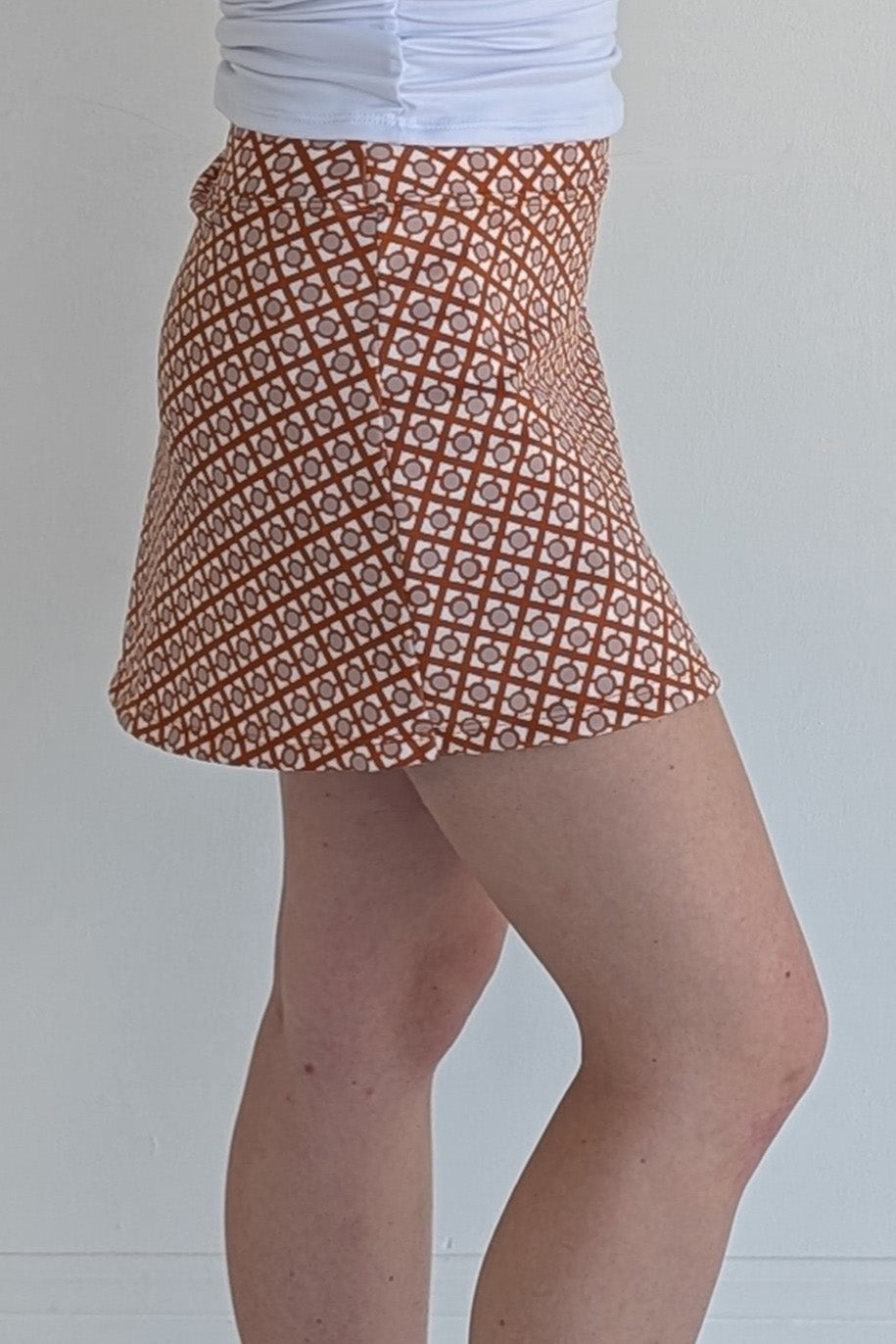 Form Fitting burnt orange miniskirt with geometric print and built in shorts and pockets; great for gameday or hanging out with friends.