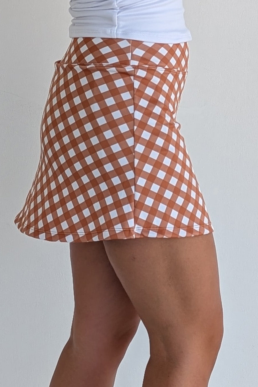Form Fitting burnt orange gingham miniskirt with  built in shorts and pockets; great for gameday or hanging out with friends.