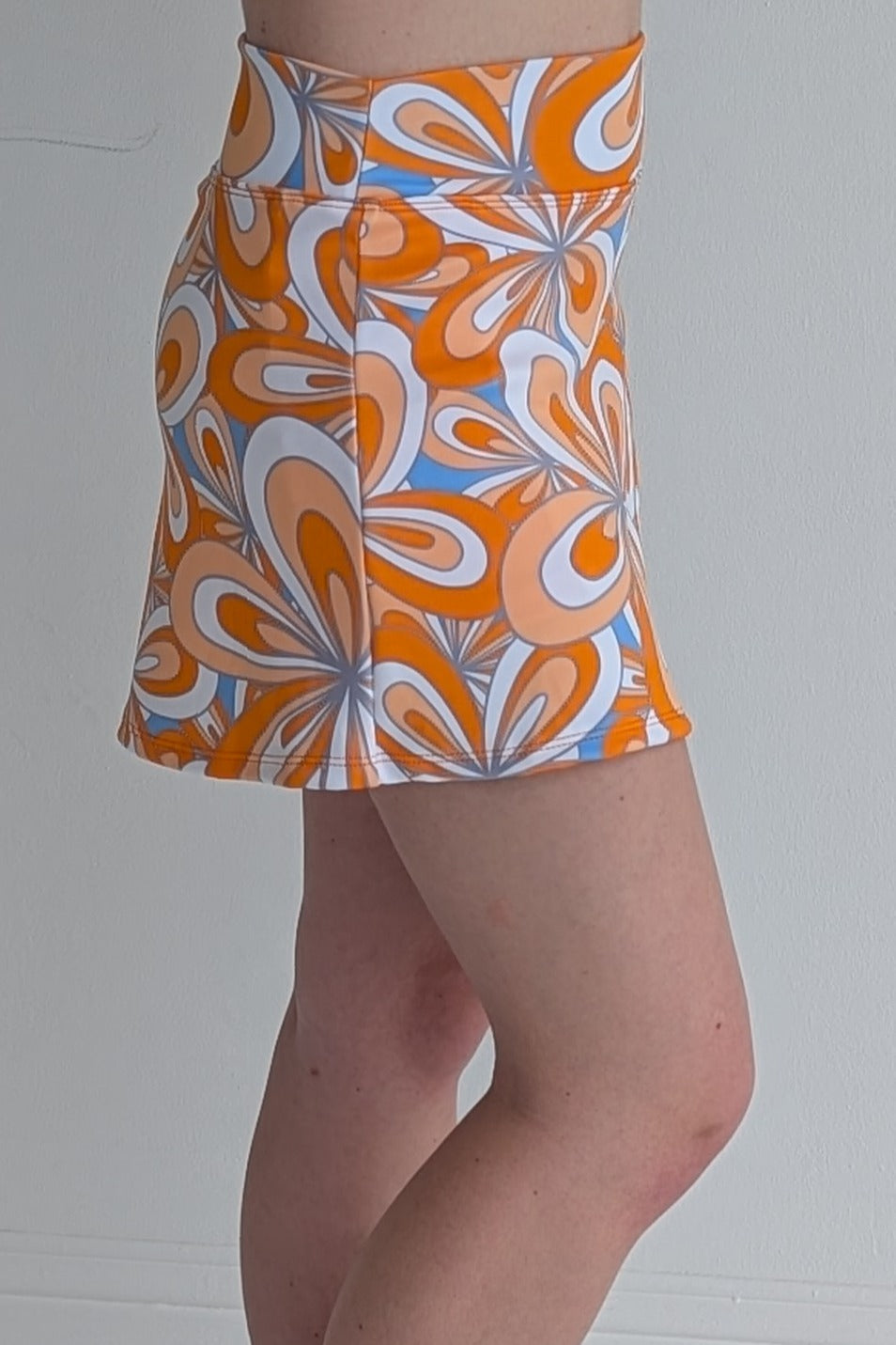 Form Fitting orange miniskirt with 70's inspired flower print and built in shorts and pockets; great for gameday or hanging out with friends.