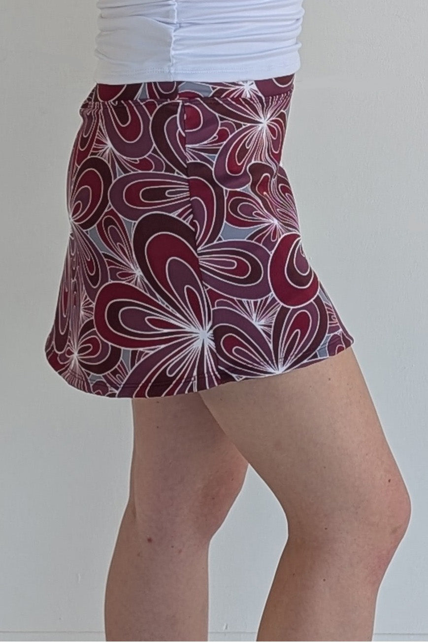 Form Fitting maroon miniskirt with 70's inspired flower print and built in shorts and pockets; great for gameday or hanging out with friends.