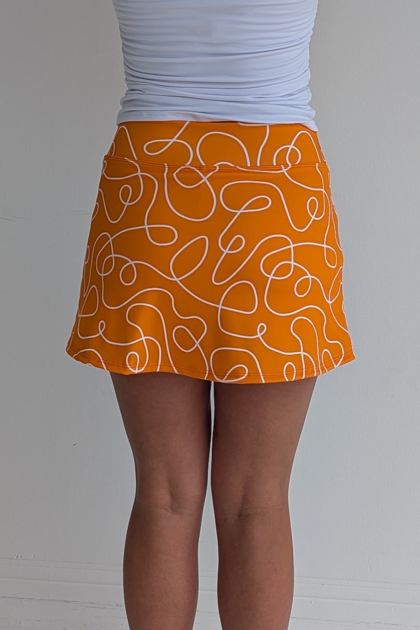 Form Fitting orange miniskirt with scribbles print and built in shorts and pockets; great for gameday or hanging out with friends.