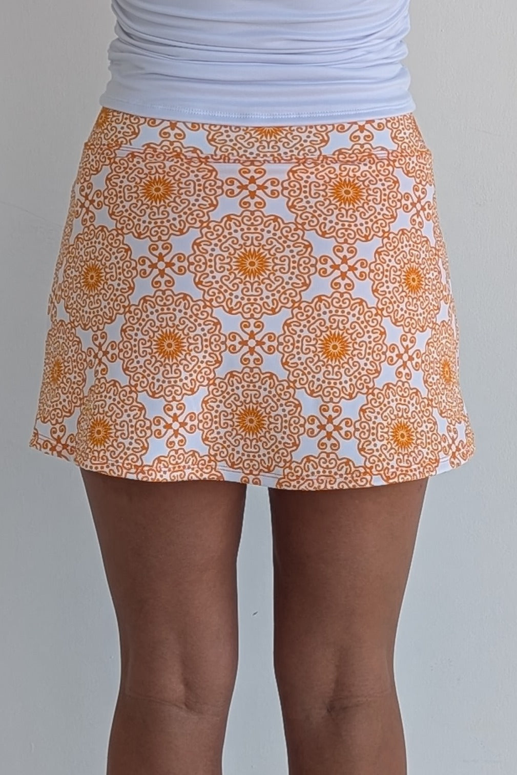 Form Fitting orange miniskirt with scroll print and built in shorts and pockets; great for gameday or hanging out with friends.