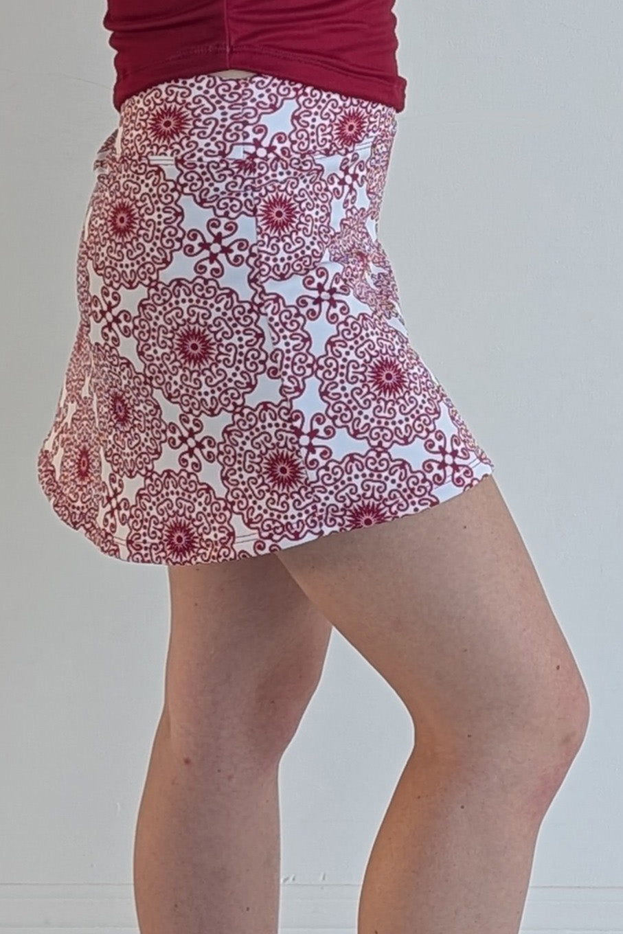 Form Fitting crimson miniskirt with scroll print and built in shorts and pockets; great for gameday or hanging out with friends.