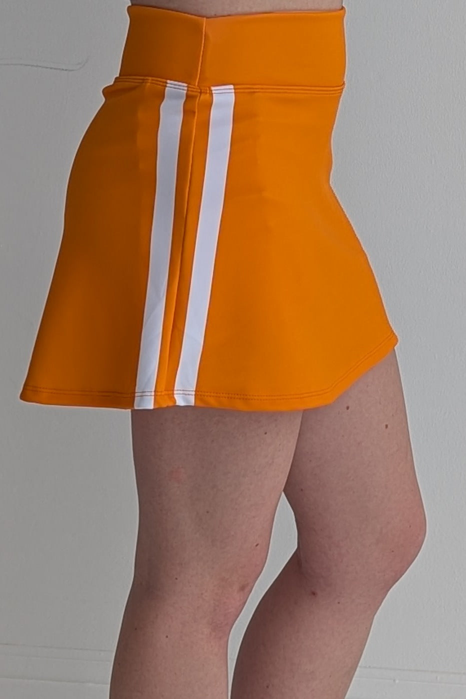 Form Fitting orange miniskirt with side stripes and built in shorts and pockets; great for gameday or hanging out with friends.