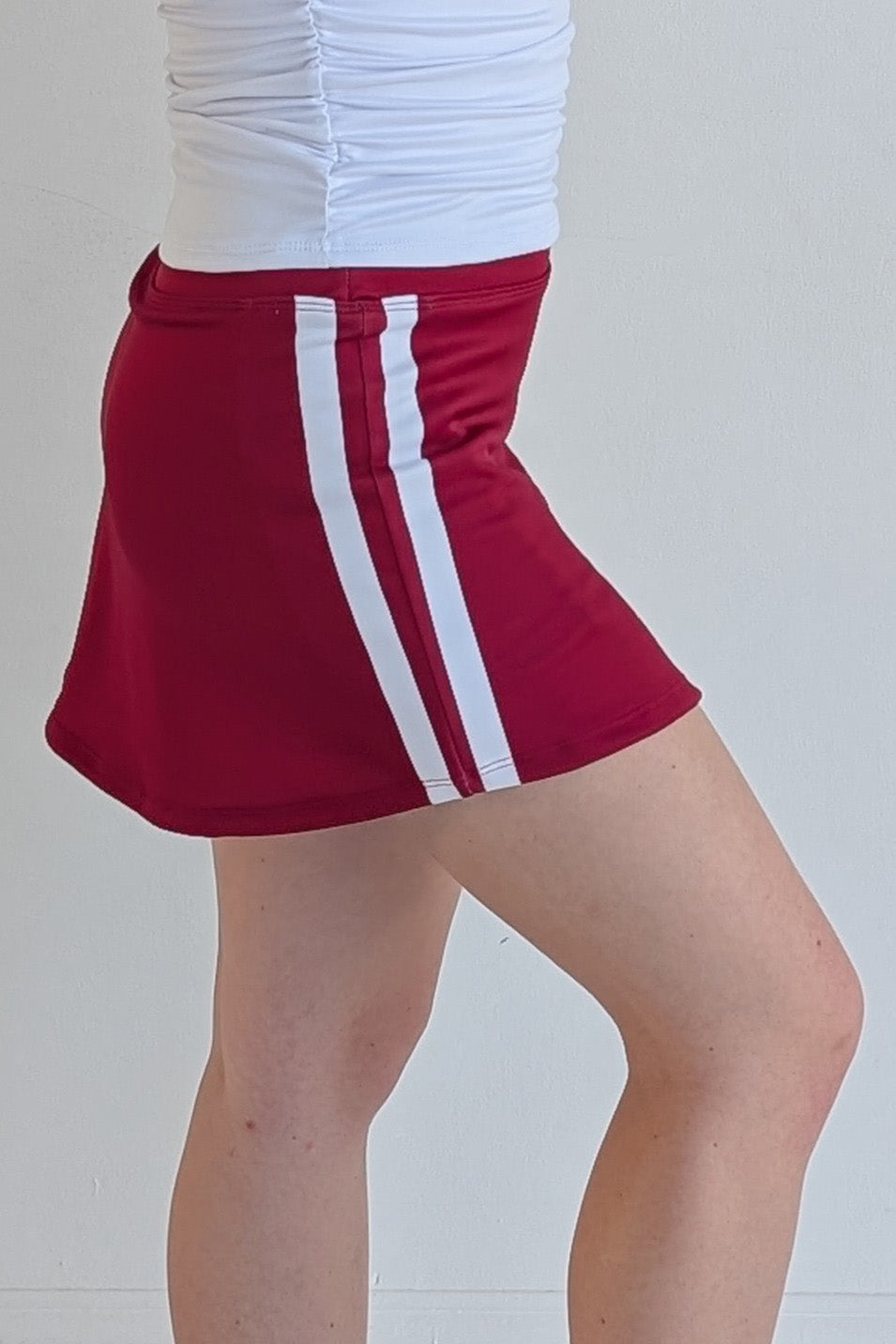Form Fitting crimson miniskirt with side stripes and built in shorts and pockets; great for gameday or hanging out with friends.