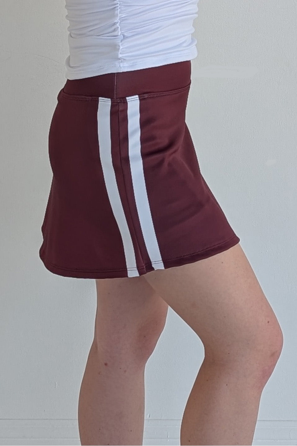 Form Fitting maroon miniskirt with side stripes and built in shorts and pockets; great for gameday or hanging out with friends.