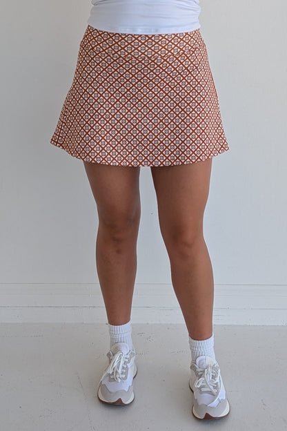Relaxed back burnt orange miniskirt with geometric print and built in shorts and pockets; great for gameday or hanging out with friends.