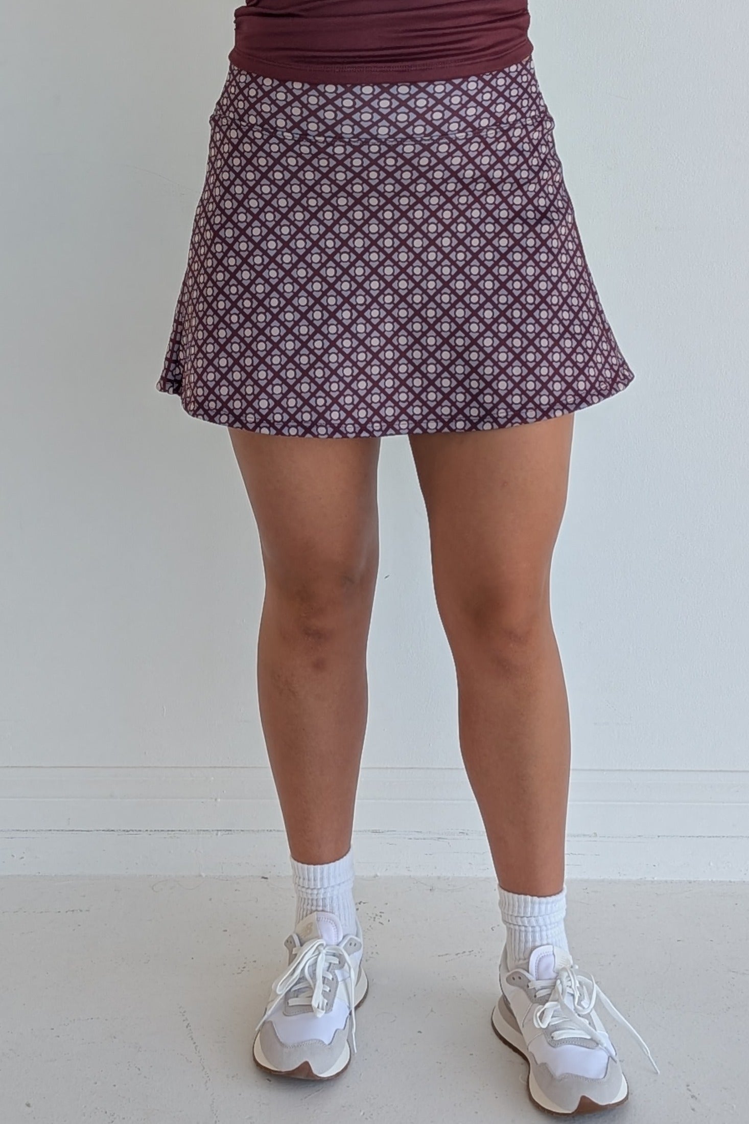 Relaxed back maroon miniskirt with geometric print and built in shorts and pockets; great for gameday or hanging out with friends.