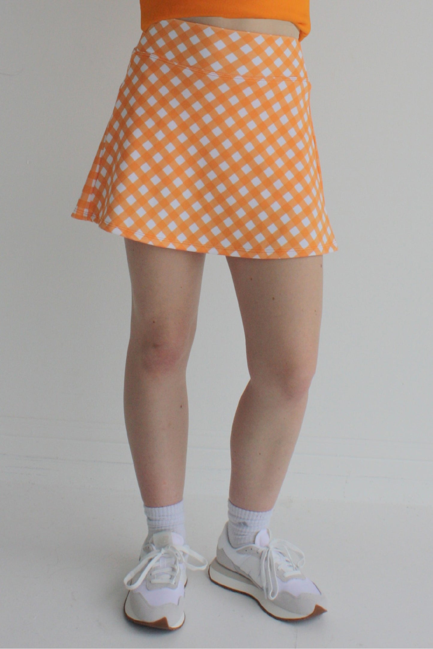 Relaxed back orange gingham miniskirt with  built in shorts and pockets; great for gameday or hanging out with friends.