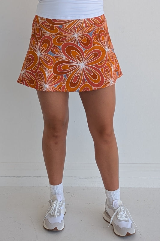 Relaxed back burnt orange miniskirt with 70's inspired flower print and built in shorts and pockets; great for gameday or hanging out with friends.