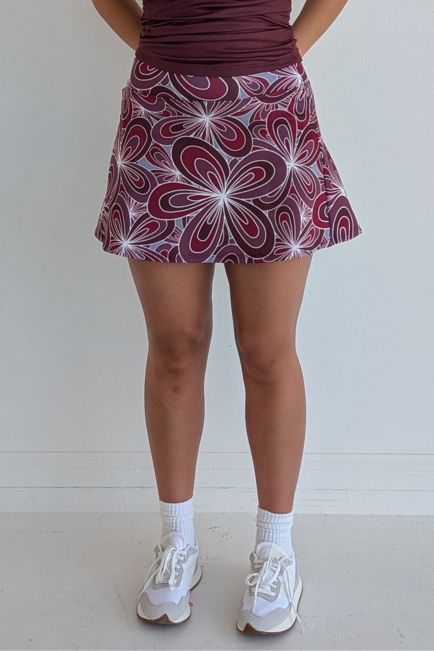 Relaxed back maroon miniskirt with 70's inspired flower print and built in shorts and pockets; great for gameday or hanging out with friends.