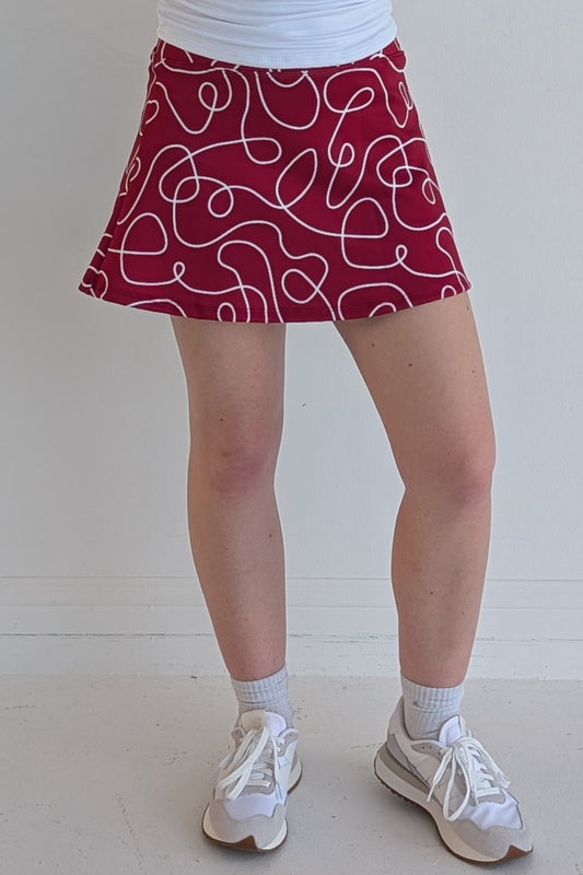 Relaxed back crimson miniskirt with scribbles print and built in shorts and pockets; great for gameday or hanging out with friends.