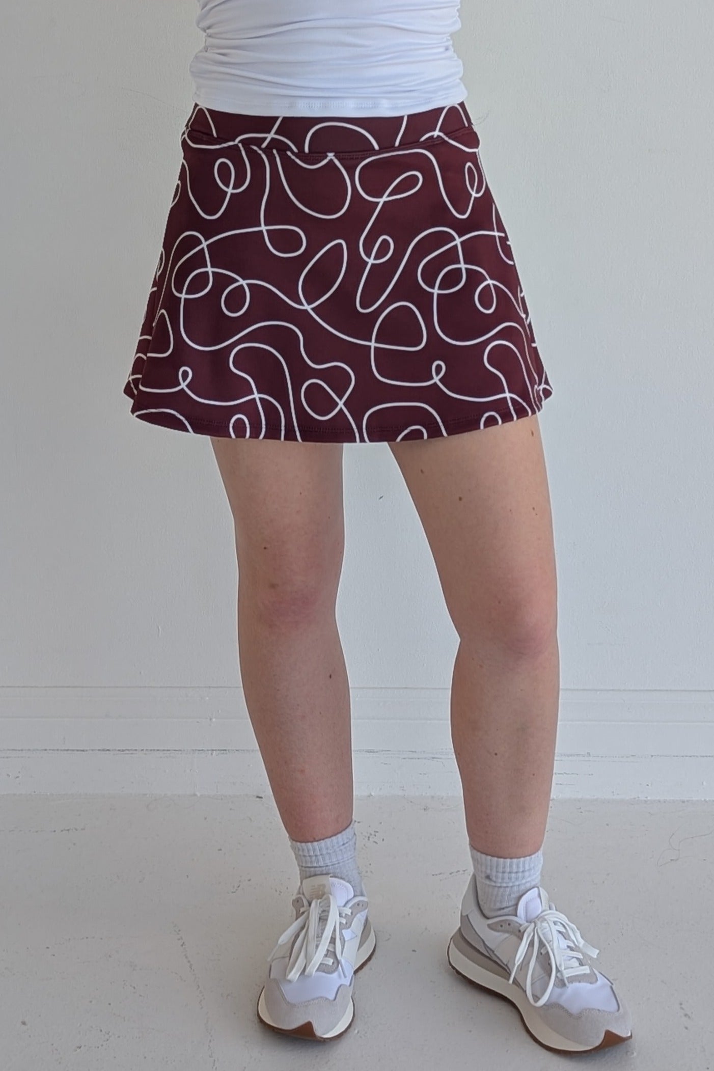 Relaxed back maroon miniskirt with scribbles print and built in shorts and pockets; great for gameday or hanging out with friends.