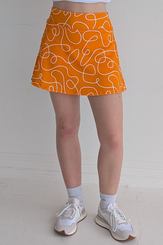 Relaxed back orange miniskirt with scribbles print and built in shorts and pockets; great for gameday or hanging out with friends.