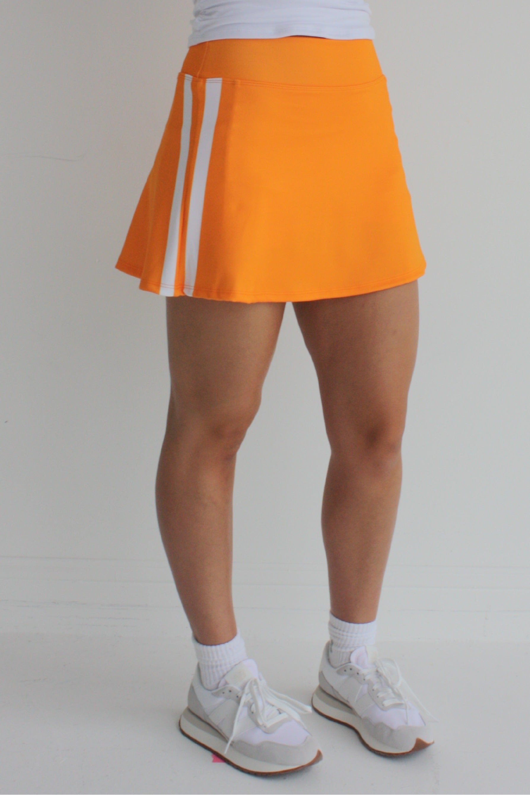 Relaxed back orange miniskirt with side stripes and built in shorts and pockets; great for gameday or hanging out with friends.
