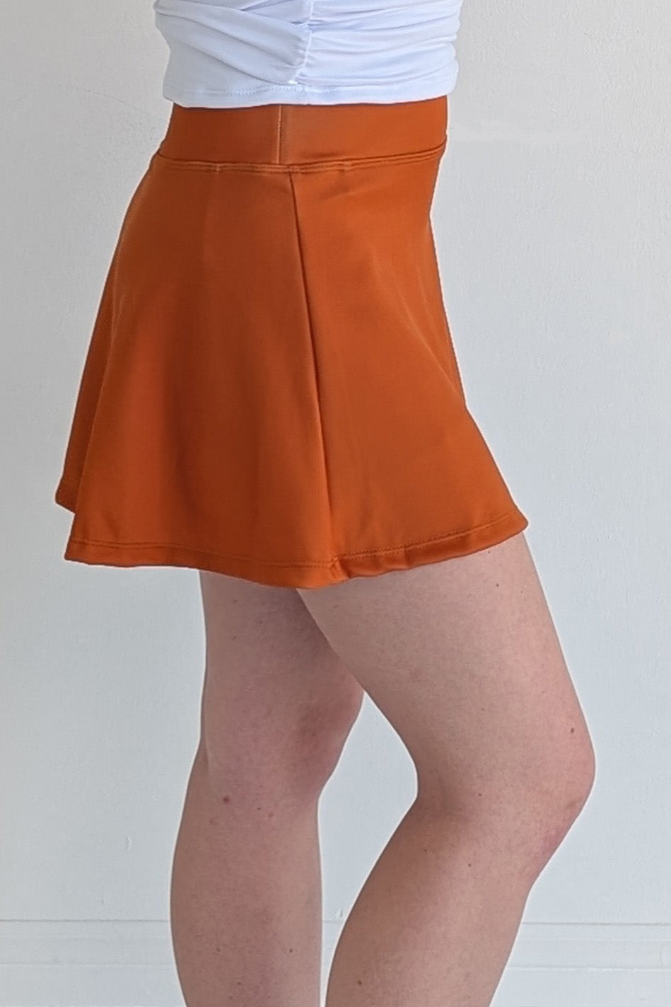 Relaxed back solid burnt orange miniskirt with built in shorts and pockets; great for gameday or hanging out with friends.