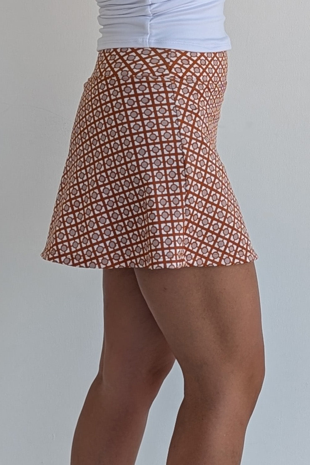 Relaxed back burnt orange miniskirt with geometric print and built in shorts and pockets; great for gameday or hanging out with friends.