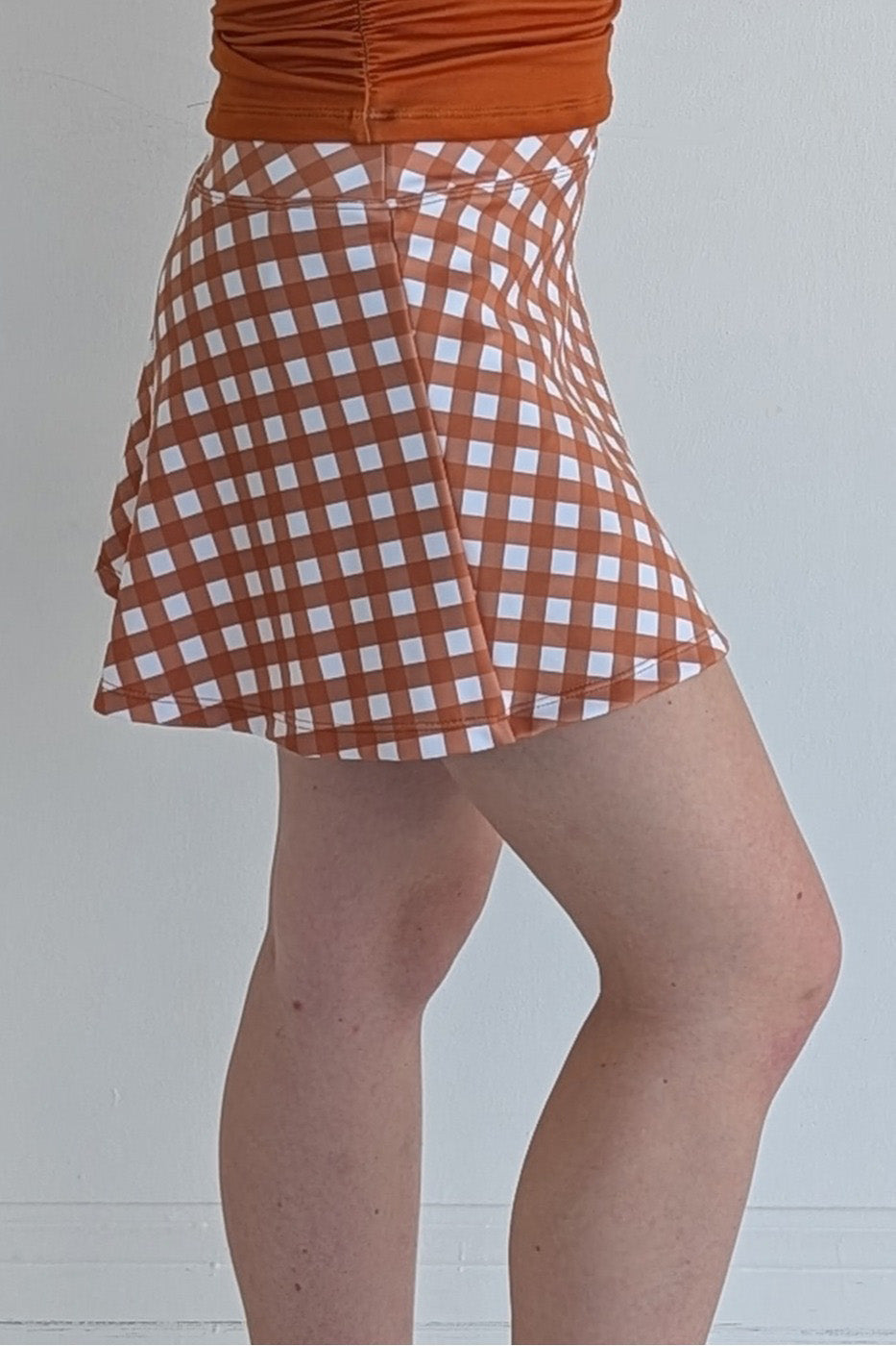 Relaxed back burnt orange gingham miniskirt with  built in shorts and pockets; great for gameday or hanging out with friends.