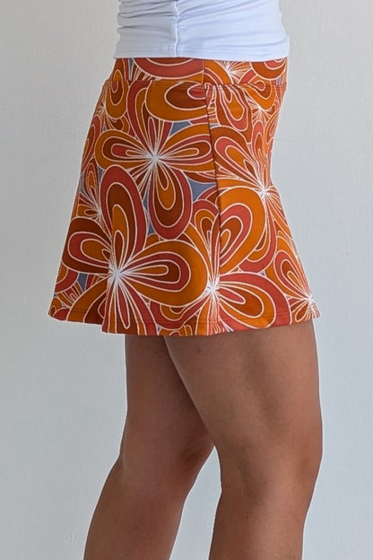 Relaxed back burnt orange miniskirt with 70's inspired flower print and built in shorts and pockets; great for gameday or hanging out with friends.