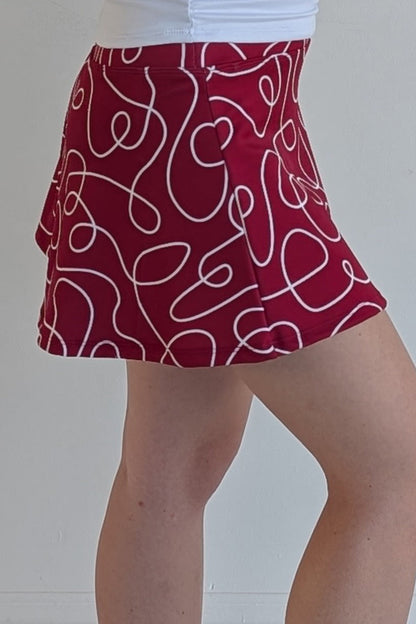 Relaxed back crimson miniskirt with scribbles print and built in shorts and pockets; great for gameday or hanging out with friends.