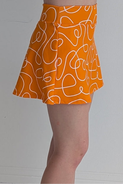 Relaxed back orange miniskirt with scribbles print and built in shorts and pockets; great for gameday or hanging out with friends.