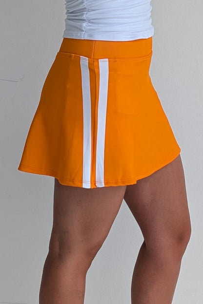 Relaxed back orange miniskirt with side stripes and built in shorts and pockets; great for gameday or hanging out with friends.