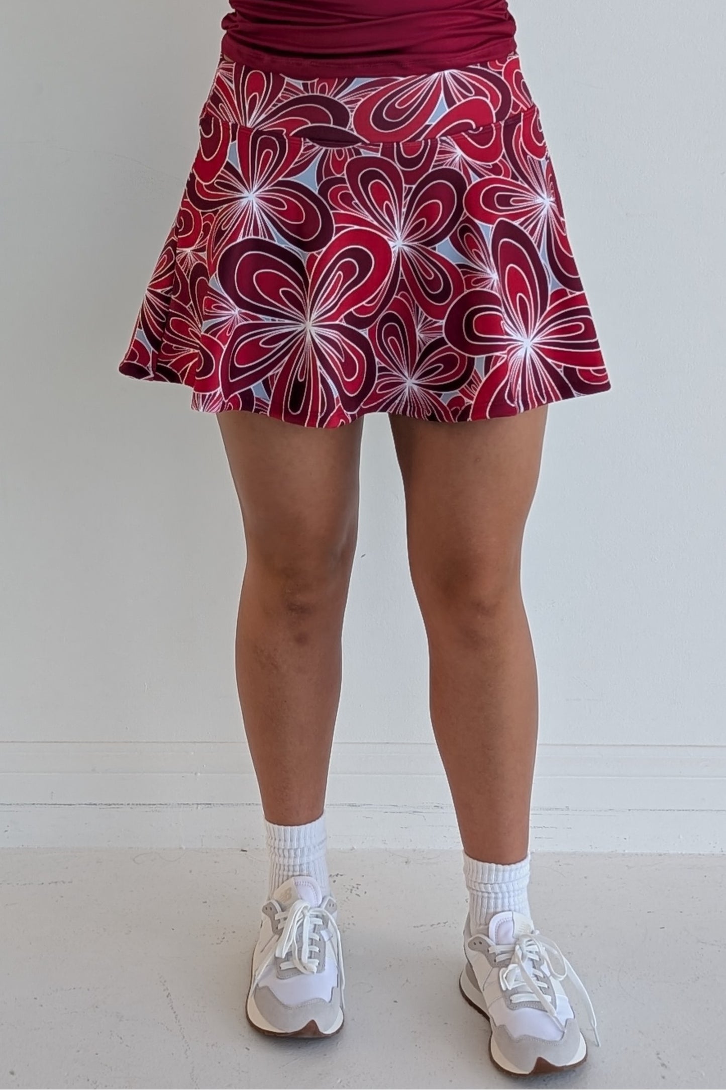 Full bodied crimson miniskirt with 70's inspired flower print and built in shorts and pockets; great for gameday or hanging out with friends.