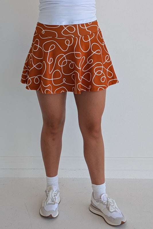 Full bodied burnt orange miniskirt with scribbles print and built in shorts and pockets; great for gameday or hanging out with friends.